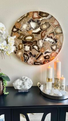 a black table with candles and flowers on it next to a wall mounted circular mirror