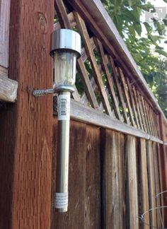 an outdoor light attached to the side of a wooden fence