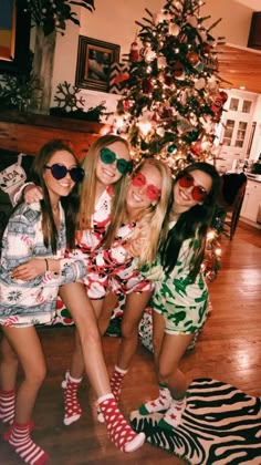 three girls in front of a christmas tree wearing matching sunglasses and socks with their arms around each other