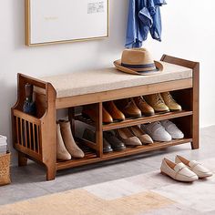 a wooden bench with shoes on it next to a mirror and coat rack in a room