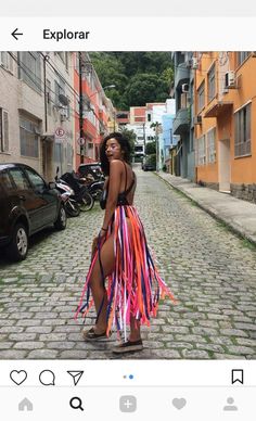 a woman in a colorful dress is standing on the street