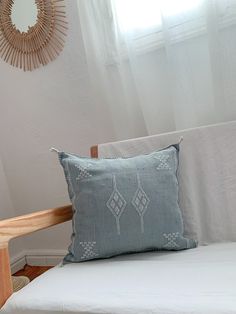 a white couch with a blue pillow on top of it next to a wooden chair