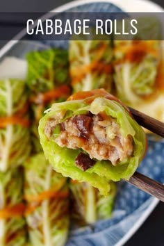 some lettuce with meat and carrots on a blue and white plate next to chopsticks