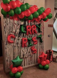 some red and green balloons are hanging on a wall with the words merry christmas spelled in large letters