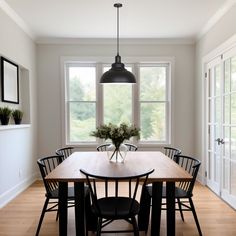 a dining room table with chairs and a vase filled with flowers sitting on top of it