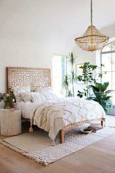 a bedroom with a bed, rug and plants on the floor in front of a window