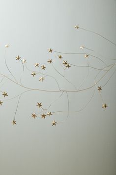 some gold stars are hanging from the ceiling in front of a white wall and floor