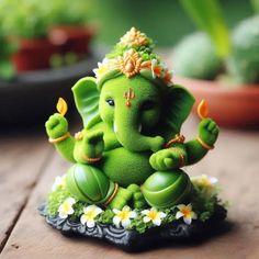 a small green statue of an elephant sitting on top of a wooden table next to potted plants