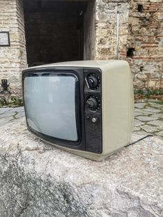 an old tv sitting on top of a rock