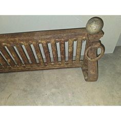 an old wooden bench sitting on top of a cement floor next to a white wall