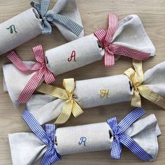 four rolled up napkins with bows and monogrammed letters are on the table