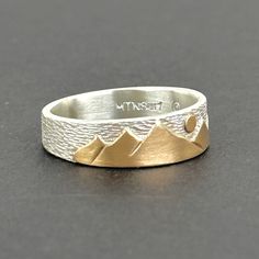 a silver and gold ring with mountains on it