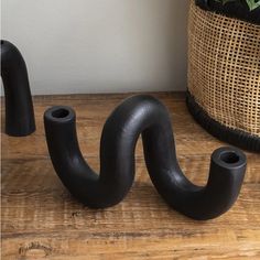 two black pipe holders sitting on top of a wooden table next to a potted plant