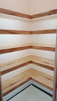 the corner of an empty room with wood slats on the walls and flooring