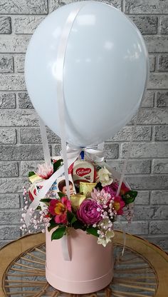 a balloon and flowers in a pink bucket