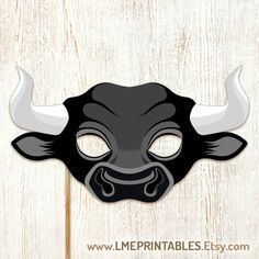 a black bull mask with white horns on a wooden background that says printable masks