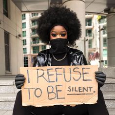 a woman with an afro holding a sign that says i refuse to be silent,