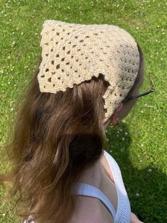 a woman wearing a crocheted hat on top of her head in the grass