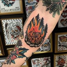 a man's arm with tattoos on it and fire in the center, surrounded by framed pictures