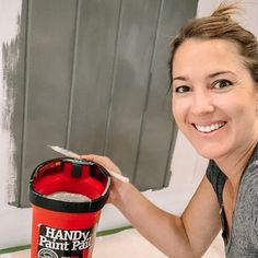 a woman is holding a paint bucket and smiling at the camera while she holds it in her hand