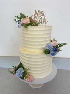 a three tiered cake with flowers and a mr and mrs sign on the top