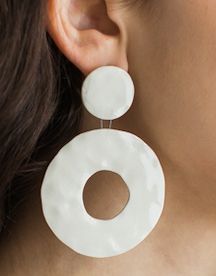 a close up of a person wearing large white earring with circular design on it