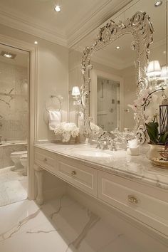 a white bathroom with marble counter tops and large mirror above the sink, along with an ornate chandelier