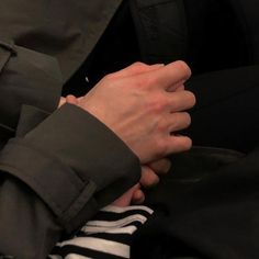 a person wearing a black jacket and striped shirt holding their hands together with both hands