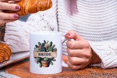 a woman is holding a croissant in her hand while sitting at a table