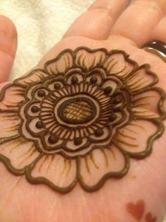 someone is holding their hand with a henna tattoo on it's palm, which looks like a flower