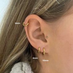 an ear with two small gold hoops attached to the side of it, and three smaller