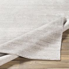 a white rug on top of a wooden floor next to a gray and white blanket