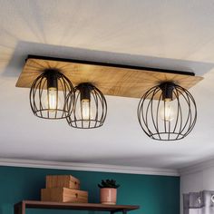 three lights hanging from the ceiling in a room with blue walls and wooden shelves on either side