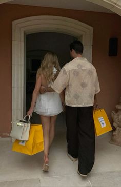 the man and woman are walking out of the building with shopping bags in their hands