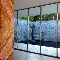 the reflection of a statue in a glass walled room with mirrored walls and floor to ceiling windows