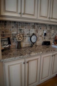 a kitchen with white cabinets and a clock on the counter top next to a sink