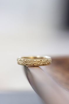 a gold wedding ring sitting on top of a wooden table