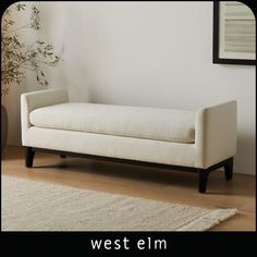 a white couch sitting on top of a wooden floor next to a potted plant