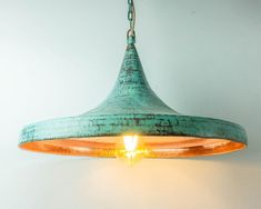 a light hanging from a ceiling fixture with a white wall in the background and a green lamp shade