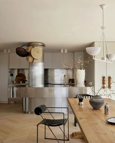 a modern kitchen with stainless steel appliances and wooden table in the foreground is a dining area