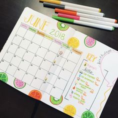 a calendar with markers and pencils next to it on top of a black table