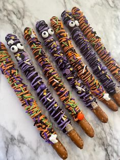 halloween pretzels decorated with candy and sprinkles are lined up on a marble surface