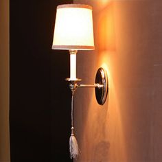 a wall lamp with a white shade on it next to a black wall and floor