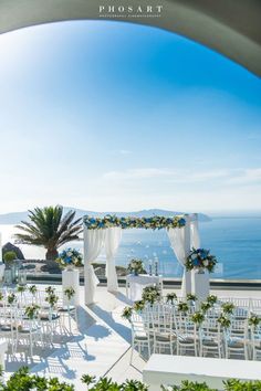 an outdoor wedding venue with white chairs and blue flowers on the aisle, overlooking the ocean