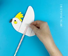 someone is cutting out a paper bird with a toothbrush on a blue table top