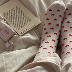 someone is laying in bed with their feet up on the pillow and reading a book