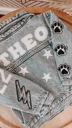 denim jacket with dog paw patches on the front and back, sitting on top of a wooden table