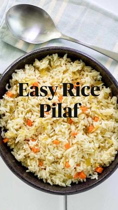 a bowl filled with rice and carrots next to a spoon on top of a table