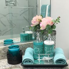 a bathroom counter with towels, soaps and flowers in vases on top of it