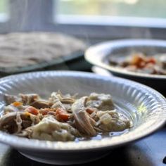 two white bowls filled with food sitting on top of a table next to a window